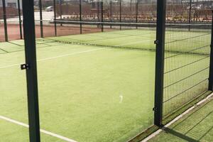 Tennis court with green grass and net outdoors photo