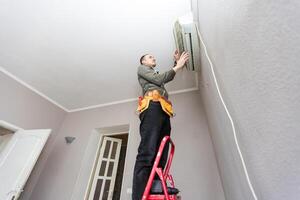 Male technician cleaning air conditioner indoors photo