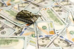 Toy tank on US hundred dollar bills banknotes close up. The concept of war costs, military spending and economic crisis photo