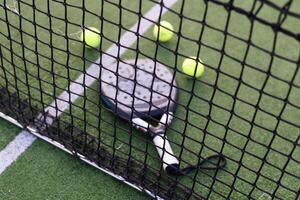 Paddle tennis racket, ball and net on the grass photo