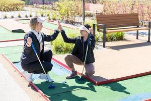 mother and daughter playing mini golf, children enjoying summer vacation photo