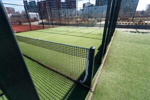 Landscaped areas of a residential development with a tennis court with high Plexiglas and metal fences photo