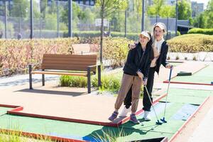 mother and daughter playing mini golf, children enjoying summer vacation photo