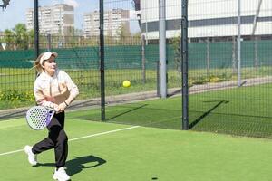 Young sporty woman performing basic strokes during paddle tennis group training photo