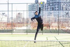Man playing padel in a green grass padel court indoor behind the net photo