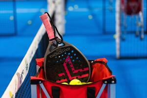 Kyiv, Ucrania, abril 18, 2024. negro profesional paleta tenis raqueta y pelota con natural Encendiendo en azul antecedentes. horizontal deporte tema póster, saludo tarjetas, encabezados, sitio web y aplicación foto