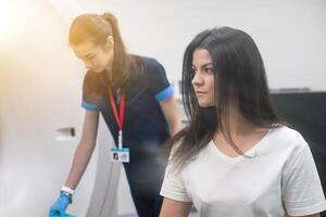 Radiologic technician and Patient being scanned and diagnosed on computed tomography scanner in hospital photo