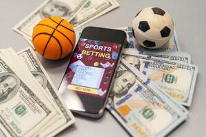 Basketball ball, smartphone with application and banknote of 100 dollars. Betting photo