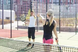 mujer padel tenis jugador formación en corte. mujer utilizando raqueta a golpear pelota. foto