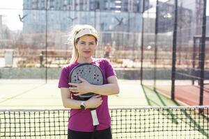 Happy female paddle tennis player during practice on outdoor court looking at camera. Copy space. photo