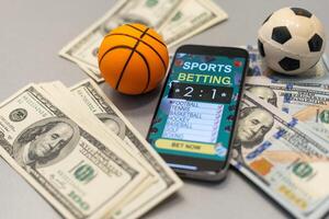 Smartphone with gambling mobile application and basketball ball with money close-up. Sport and betting concept photo