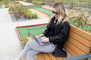 un mujer de negocios utilizando un ordenador portátil en un golf curso foto