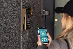 mujer cierre cerradura inteligente en el Entrada puerta utilizando un inteligente teléfono. concepto de utilizando inteligente electrónico Cerraduras con sin claves acceso. foto