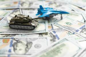 Toy tank on US hundred dollar bills banknotes close up. The concept of war costs, military spending and economic crisis photo