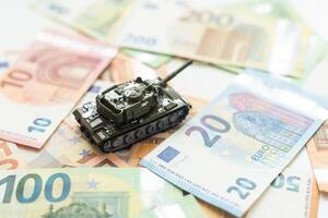 juguete tanque en nosotros cien dólar cuentas billetes cerca arriba. el concepto de guerra costos, militar gasto y económico crisis foto