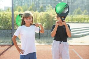 joven chicas, Atletas sacudida manos antes de juego sesión. jugando tenis en calentar soleado día a abierto aire tenis corte. concepto de deporte, pasatiempo, activo estilo de vida, salud, resistencia y fortaleza, anuncio foto