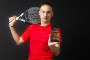 man holding paddel racket and smartphone with bet black background photo