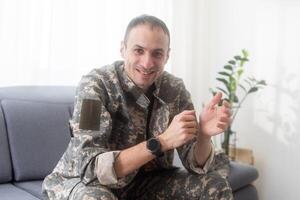 excited army soldier sitting on couch at home photo