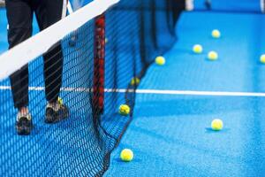 Twoo balls next to the net of a blue paddle tennis court. Sport healthy concept. photo