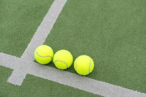 Yellow balls on grass turf near padel tennis racket behind net in green court outdoors with natural lighting. Paddle is a racquet game. Professional sport concept with copy space. photo