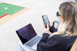 woman on golf course with smartphone with sports betting app photo