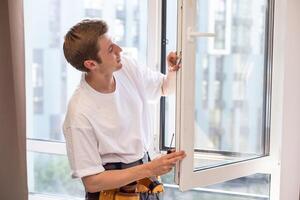 a repairman repairs, adjusts or installs metal-plastic windows in the apartment. glazing of balconies, loggias, verandas in house. production of double-glazed windows to individual sizes photo