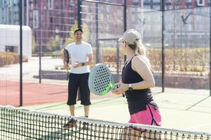 Deportes Pareja con padel raquetas posando en tenis Corte foto