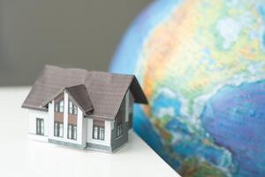 House miniature with globe in background against plain wall photo