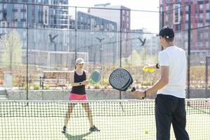 Sports couple with padel rackets posing on tennis court photo