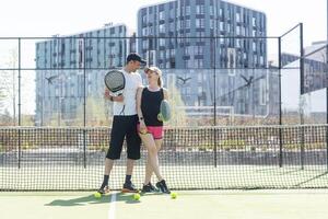 Deportes Pareja con padel raquetas posando en tenis Corte foto