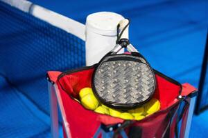 negro profesional paleta tenis raqueta y pelota con natural Encendiendo en azul antecedentes. horizontal deporte tema póster, saludo tarjetas, encabezados, sitio web y aplicación foto