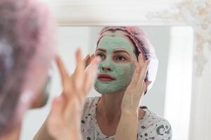 mujer utilizar un facial mascarilla. ella es mirando en el espejo. foto