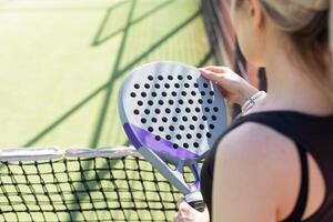 hands of a woman paddle player is holding balls and the racket at the background at the beginning of the match outdoors photo