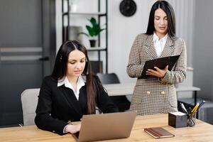 Call center agent with headset working on support hotline in modern office. Two young attractive women are working in the office photo