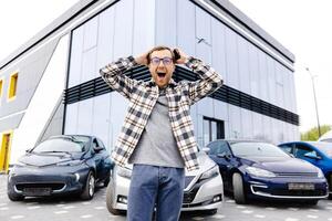 A young man is very impressive and happy, standing in front of his new car photo