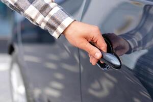 joven hombre comprando auto a concesión salón y apertura el puerta de su coche foto