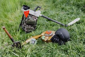 Explosive devices and a metal detector lie on the background of a forest massif. Equipment for demining the territory photo