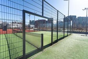 Landscaped areas of a residential development with a tennis court with high Plexiglas and metal fences photo