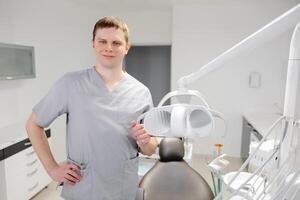 Dentist at workplace. Cheerful doctor standing in modern office and looking at camera photo