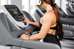 Attractive young sports woman is working out in gym, she doing cardio training on treadmill. Running on treadmill. photo