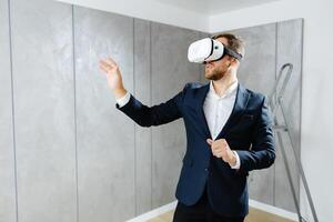 Young man wearing VR glasses, scrolling with hands in air using futuristic innovative technology choosing home design. Repair and renovation concept. Virtual reality photo