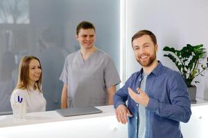 Grateful patient. Man standing at the reception of dental clinic and very pleased for the treatment. photo