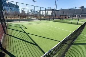 ajardinado areas de un residencial desarrollo con un tenis Corte con alto plexiglás y metal vallas foto