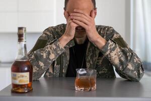 Military Drug and alcohol abuse concept. Closeup of soldier with whiskey and pills to treat his PTSD symptoms. photo