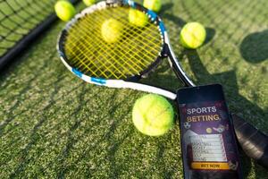 Ball with red racket leaning on tennis net at court during sunny day. unaltered, sport and tennis game concept. photo