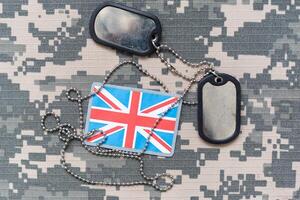 army blank, dog tag with flag of great britain on the khaki texture background. military concept photo