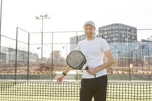 European man holding padel racquet in hand and ready to return ball while playing in court photo