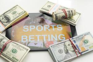 tablet pc with app for sport bets, on top of stacks of banknotes, white background, concept of online bets 3d render photo