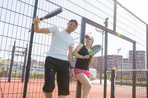 Ucrania Kyiv, abril 02 2024. contento atlético Pareja teniendo divertido mientras jugando padel tenis dobles partido en al aire libre corte. foto