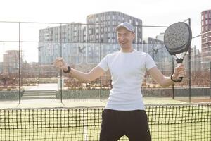 European man holding padel racquet in hand and ready to return ball while playing in court photo